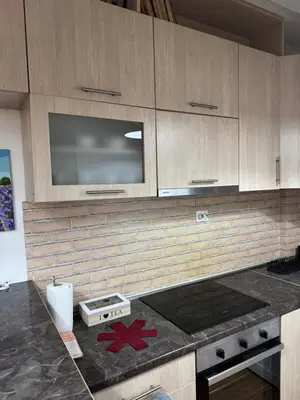 a kitchen with wooden cabinets and a counter top at Royal Central Apartment in Bar