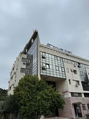 a white building with a tree in front of it at Royal Central Apartment in Bar