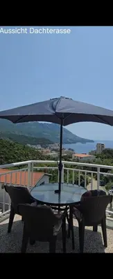 a table and chairs with an umbrella on a balcony at Sveti Georgie Apartments in Becici