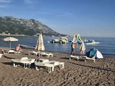a group of chairs and umbrellas on a beach with slides at Sveti Georgie Apartments in Becici
