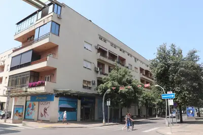 a building on a street corner with people crossing the street at Loft Apartment in Podgorica