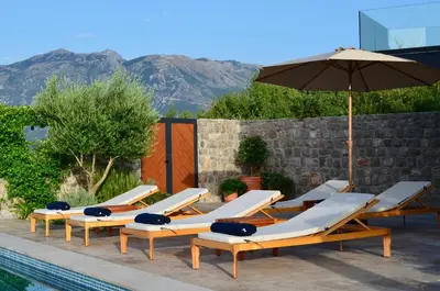 a row of lounge chairs and an umbrella next to a pool at Villa Diamonte in Ðuraševići