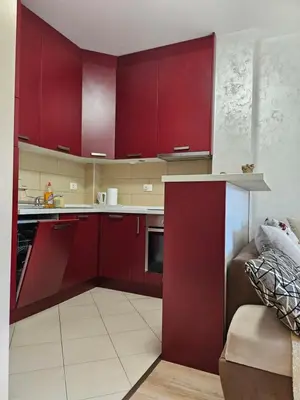 a kitchen with red cabinets and a couch at Apartmans Budva centar in Budva