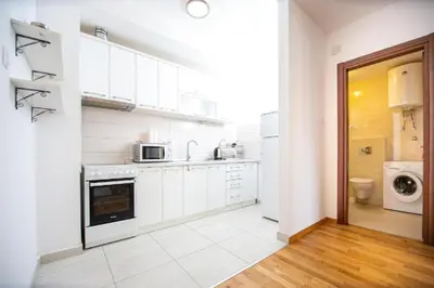 a kitchen with white cabinets and a washer and dryer at Apartmans Budva centar in Budva
