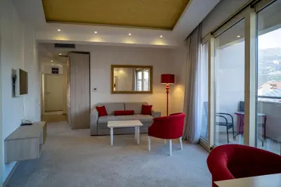 a living room with a couch and red chairs at Hotel Atina in Budva