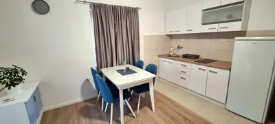 a kitchen with a white table and blue chairs at Apartment Folic Sutomore in Sutomore