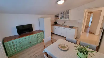 a kitchen with a table and a television on a cabinet at Apartment Folic Sutomore in Sutomore
