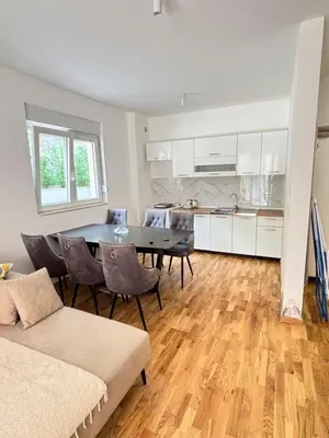 a living room with a table and chairs and a kitchen at Becici Garden in Becici