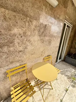 a yellow table and chairs next to a stone wall at Becici Garden in Becici