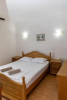 a bedroom with a bed with white sheets and two night stands at Villa Duraku in Ulcinj