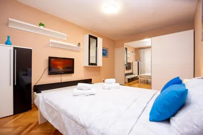 a bedroom with a large white bed with blue pillows at Palm street apartment near Dukley beach in Budva