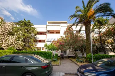 two cars parked in a parking lot in front of a building at Palm street apartment near Dukley beach in Budva