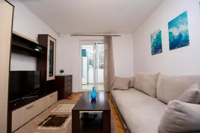 a living room with a couch and a tv at Palm street apartment near Dukley beach in Budva