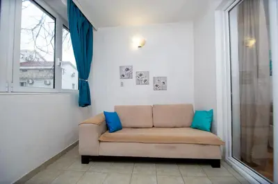 a couch sitting in a room with a window at Palm street apartment near Dukley beach in Budva