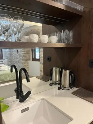 a kitchen counter with a sink and glasses on a shelf at Casa Del Sol Pietra Kotor in Kotor