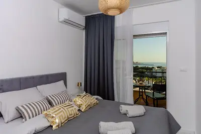 a bedroom with a bed with pillows and a balcony at Alpha Mare in Bar