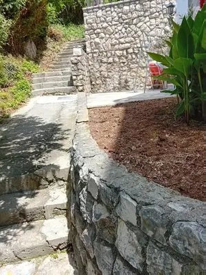 a stone retaining wall next to a path at Mota saste mini duplex in Sveti Stefan