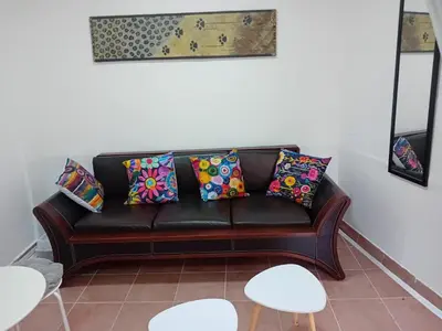 a black leather couch with colorful pillows in a living room at Mota saste mini duplex in Sveti Stefan
