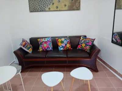 a living room with a black couch and white chairs at Mota saste mini duplex in Sveti Stefan