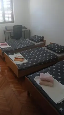 two twin beds in a room with a table at Apartman Lastva in Lastva