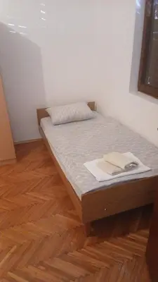 a bed in a room with a wooden floor at Apartman Lastva in Lastva