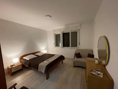 a bedroom with a bed and a chair and a mirror at Apartment Mijuskovic in Kravlja