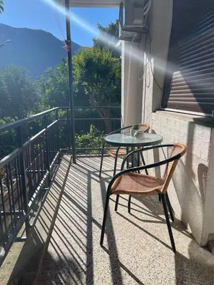 a glass table and two chairs on a balcony at Apartment Mijuskovic in Kravlja