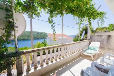 a balcony with a chair and a view of the water at Apartmani Elena in Bigovo