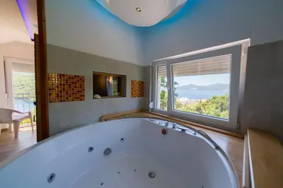 a bath tub in a room with a large window at Apartmani Elena in Bigovo