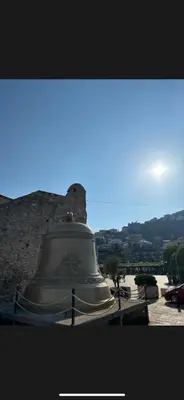 a large bell sitting next to a stone wall at Citadela Old Town Budva in Budva