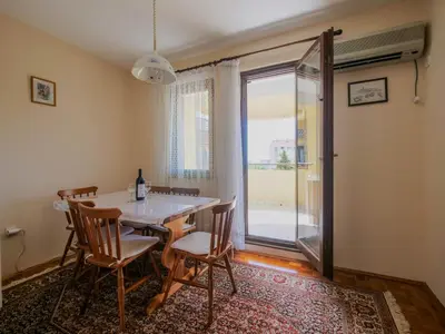 a dining room with a table and chairs and a window at Apartman Baranka in Bar