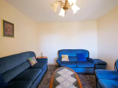 a living room with two blue couches and a chandelier at Apartman Baranka in Bar