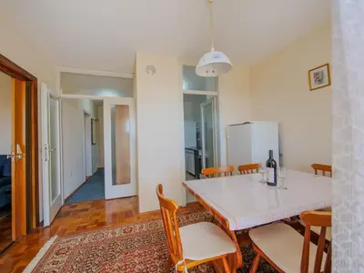 a dining room with a white table and chairs at Apartman Baranka in Bar