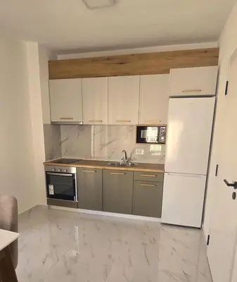 a kitchen with white cabinets and a white refrigerator at Kosara apartman Velika Plaža Ulcinj in Ulcinj