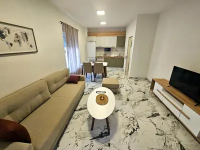 a living room with a couch and a tv and a table at Kosara apartman Velika Plaža Ulcinj in Ulcinj