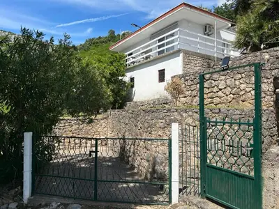 a house behind a stone wall with a green gate at Prestige House in Dobra Voda