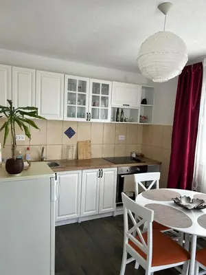 a kitchen with white cabinets and a table and a dining room at Prestige House in Dobra Voda