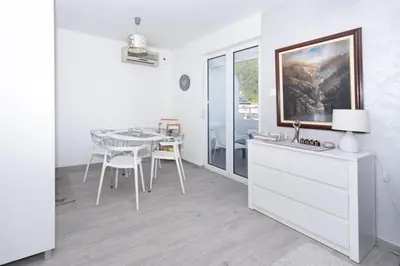 a white kitchen with a table and a dining room at Central comfy apartment in Budva