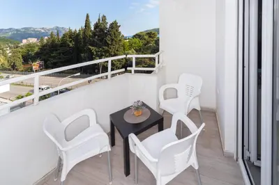 a balcony with white chairs and a table and a view at Central comfy apartment in Budva