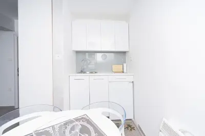 a kitchen with white cabinets and a table and chairs at Central comfy apartment in Budva