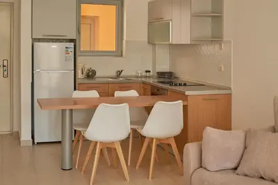a kitchen with a wooden table and white chairs at Summer Apartment with pool in Petrovac na Moru