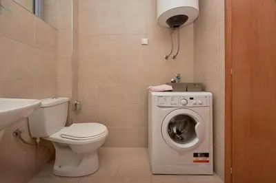 a bathroom with a toilet and a washing machine at Summer Apartment with pool in Petrovac na Moru