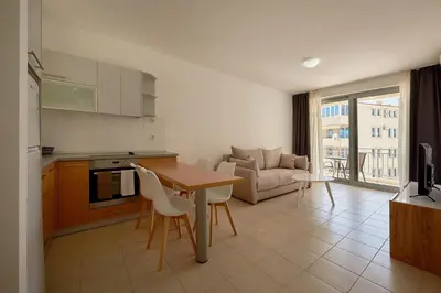 a kitchen and living room with a table and a couch at Summer Apartment with pool in Petrovac na Moru