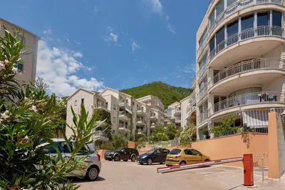 a parking lot with cars parked in front of a building at Summer Apartment with pool in Petrovac na Moru