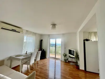 a living room with a table and chairs and a kitchen at Olive Hill Home in Becici