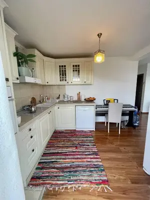 a kitchen with white cabinets and a rug on the floor at Olive Hill Home in Becici