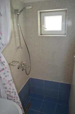 a bathroom with a shower with a blue tile floor at Lovely 1BR Apartment 5min of walk from city center in Bar