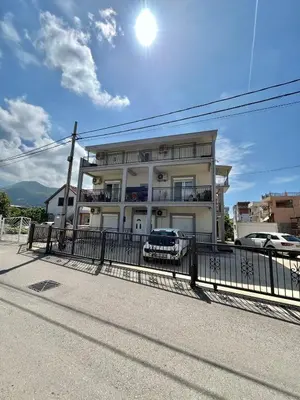 a white building with a car parked in front of it at B&V apartmani in Bar, Susanj
