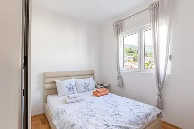 a white bedroom with a bed with towels on it at Budva Olive Escape in Budva