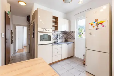 a kitchen with white cabinets and a refrigerator at Budva Olive Escape in Budva